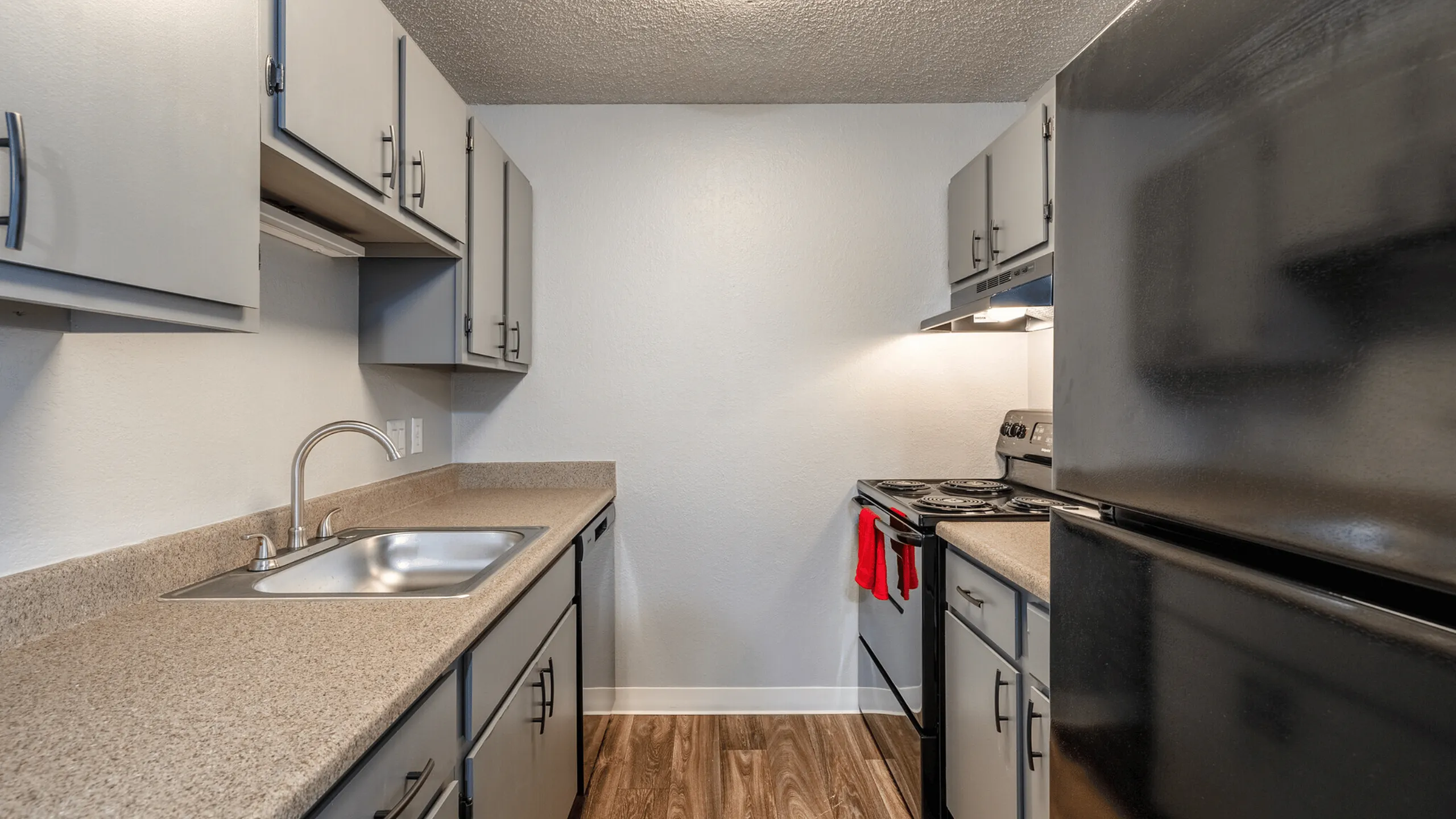 Modern kitchen with sleek gray cabinets, granite countertops, and stainless steel appliances.