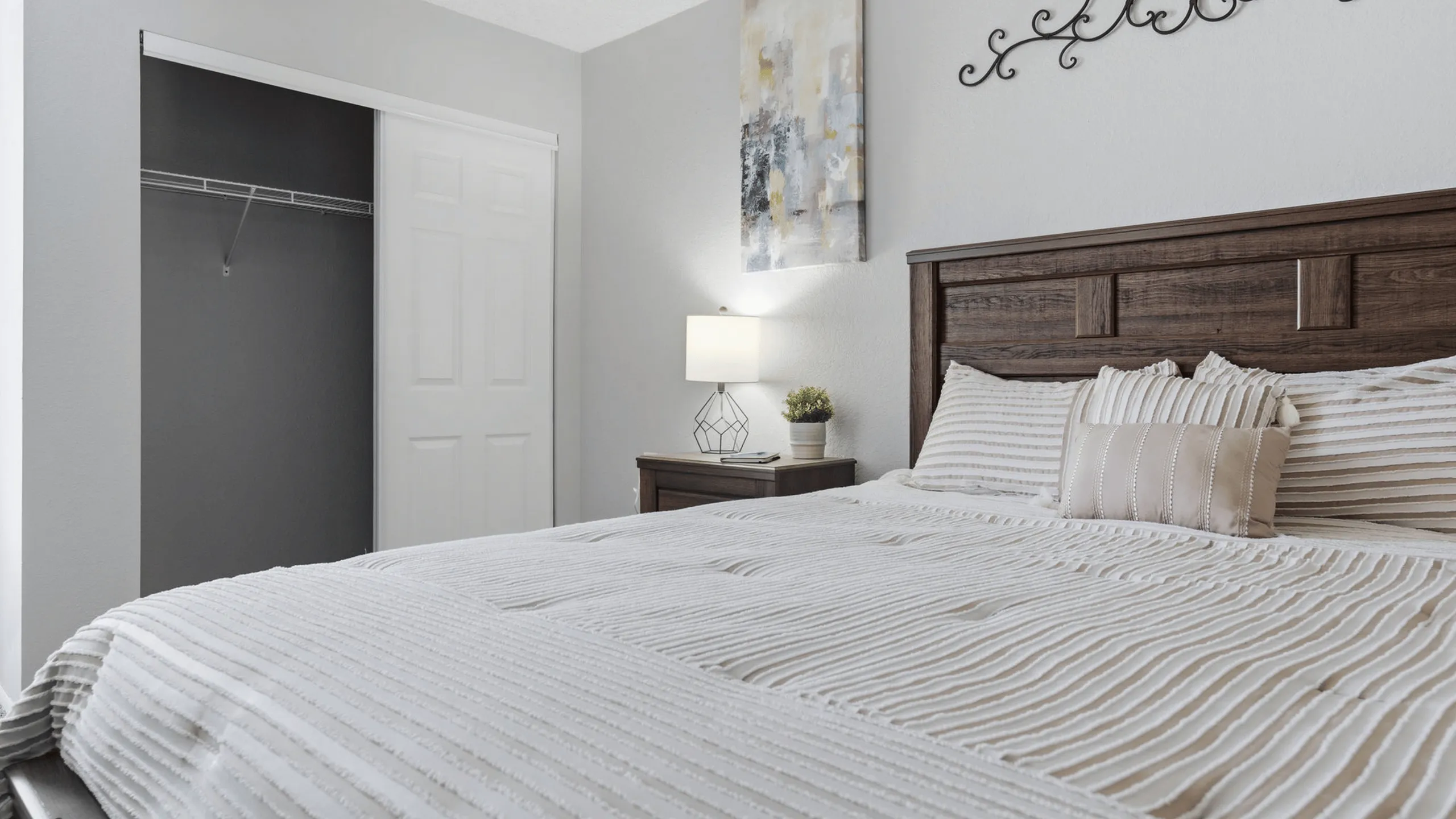 Inviting bedroom with a cozy bed, modern lamp, and elegant artwork, perfect for relaxation.