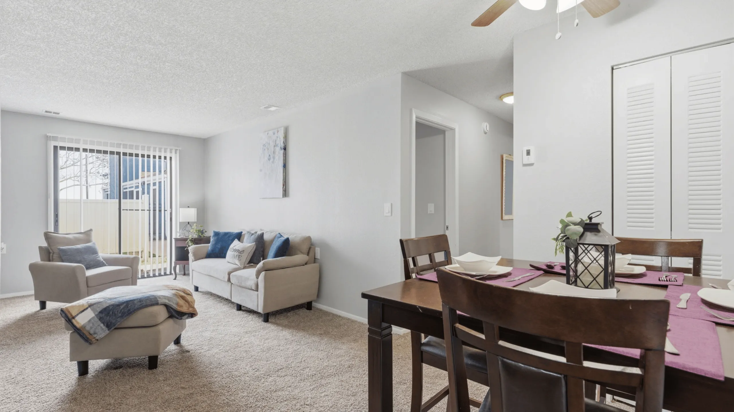 Inviting living and dining area featuring plush seating, elegant decor, and natural light through large sliding doors, perfect for comfortable living.