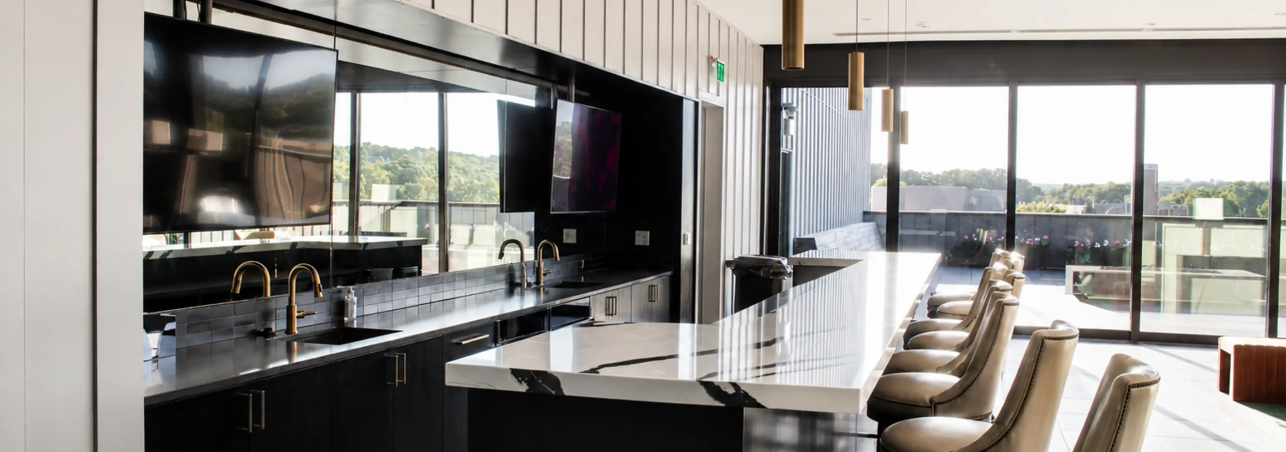 Luxurious kitchen with sleek black cabinetry, marble countertops, gold fixtures, and large windows offering breathtaking views.
