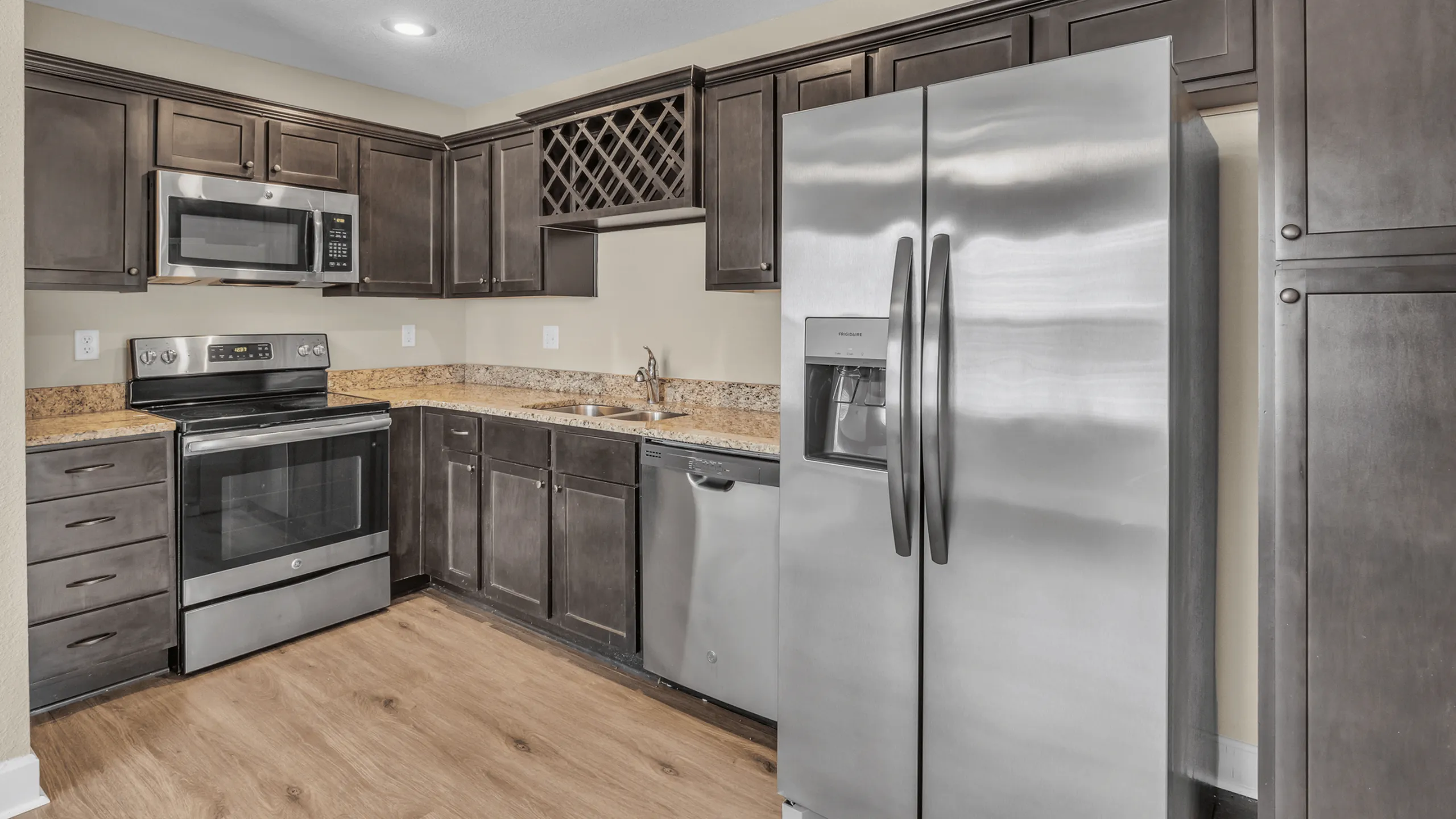 Elegant kitchen with modern stainless steel appliances, rich wood cabinetry, and granite countertops, epitomizing stylish functionality.