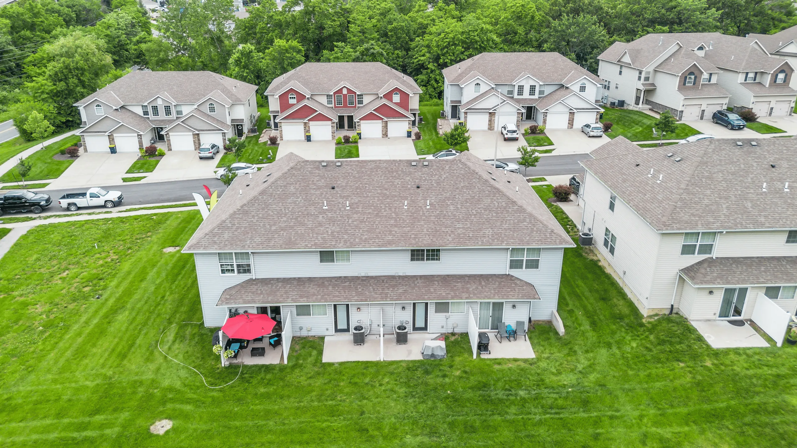 Charming suburban neighborhood showcasing rows of modern townhouses with manicured lawns and cozy patio spaces, perfect for family living.