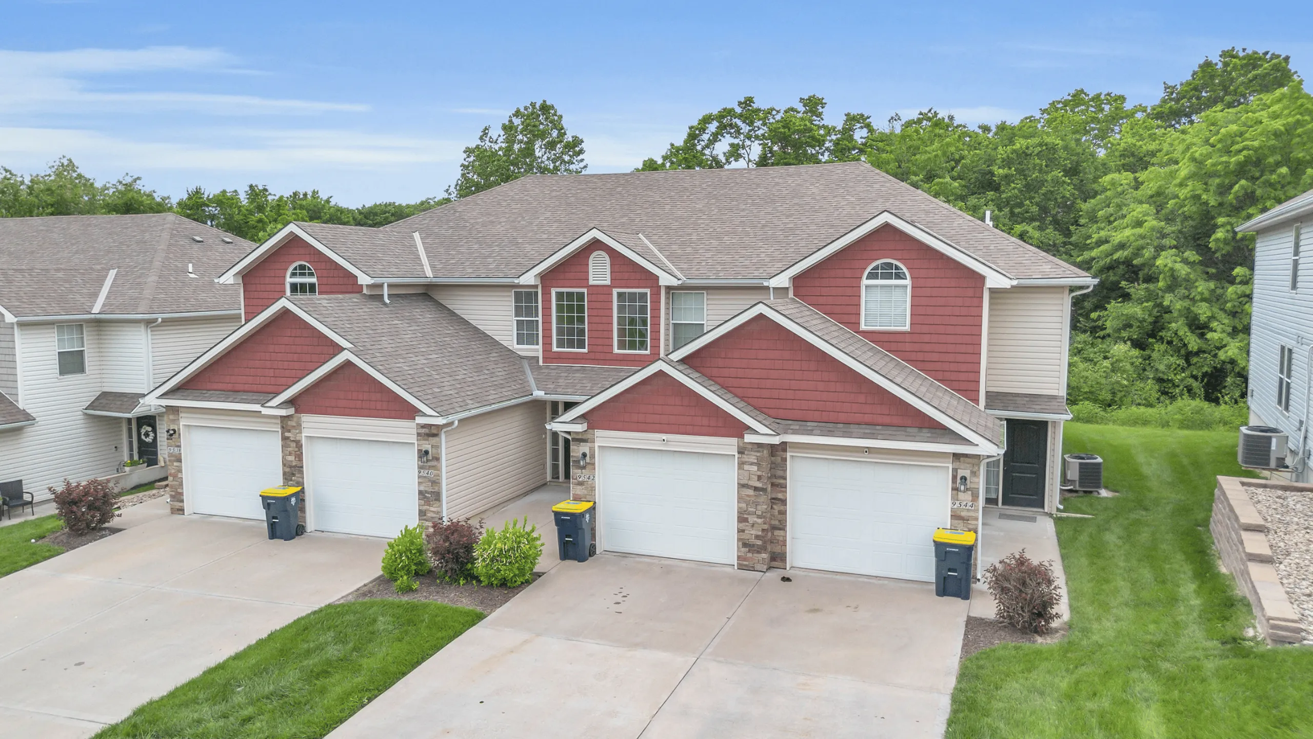 Charming duplex townhouse with modern architecture, spacious garages, and lush green surroundings perfect for family living.