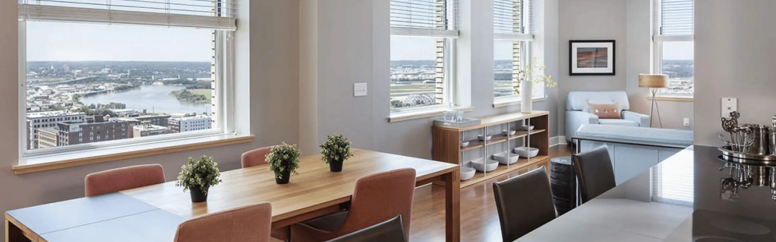 Bright and airy apartment living space featuring stylish dining area with large windows showcasing stunning city and river views.