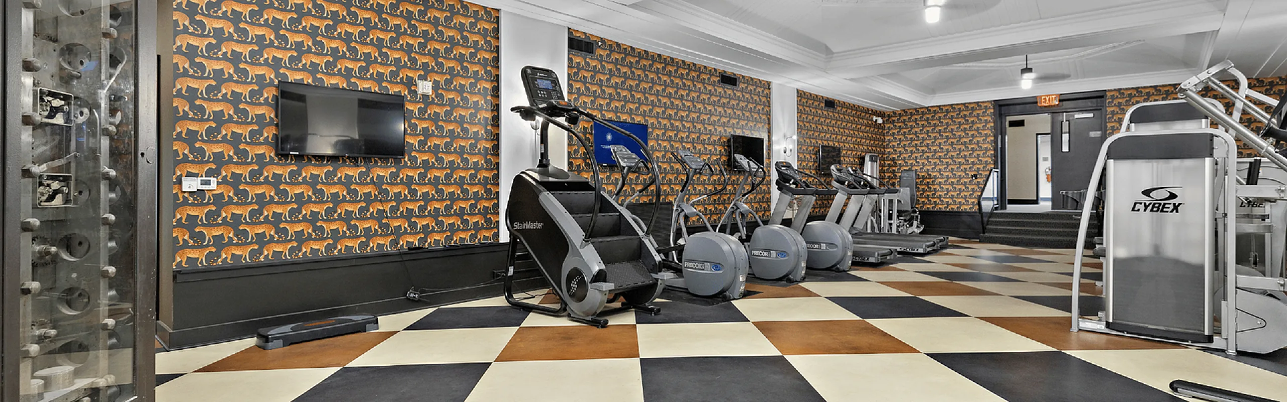 Chic apartment gym with modern exercise equipment, vibrant tiger wallpaper, and stylish checkered flooring.