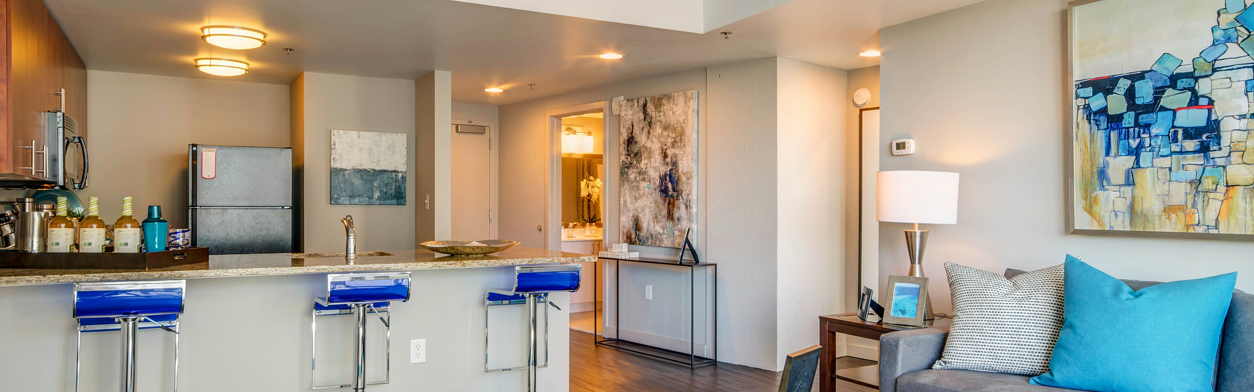 Modern apartment interior with open-concept kitchen and cozy living area featuring stylish decor and vibrant blue accents.