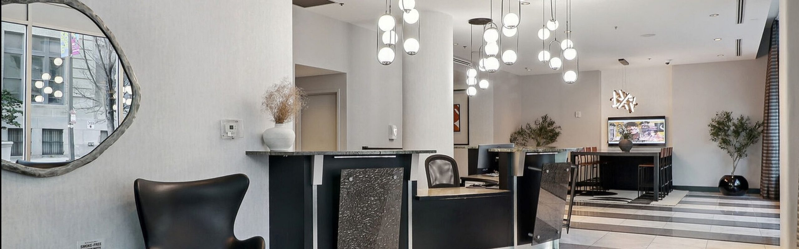 Elegant lobby with modern lighting, sleek black seating, and chic check-in desk, offering a welcoming atmosphere.