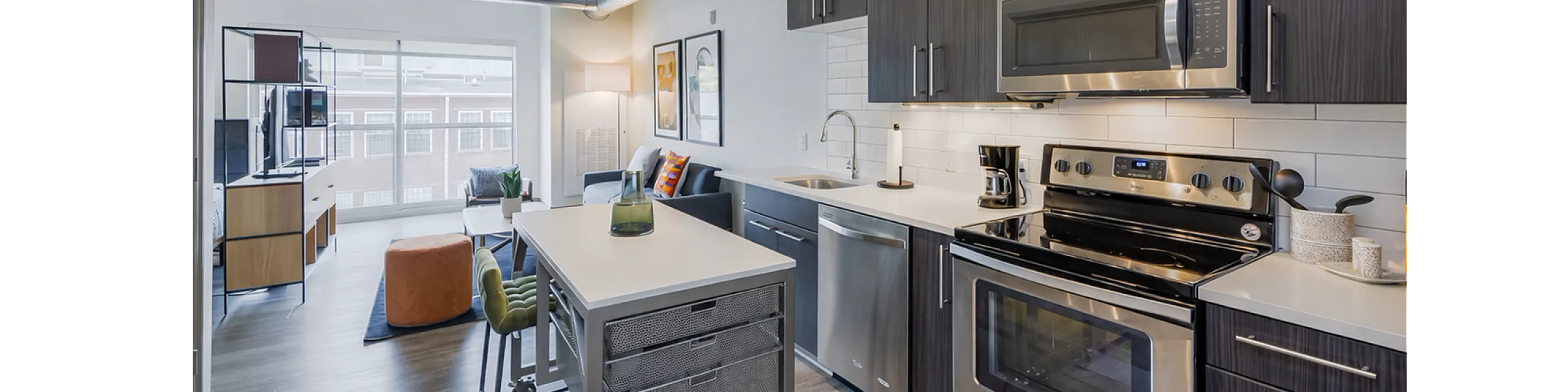 Contemporary apartment kitchen with sleek cabinetry, stainless steel appliances, and open-concept living area with modern decor.