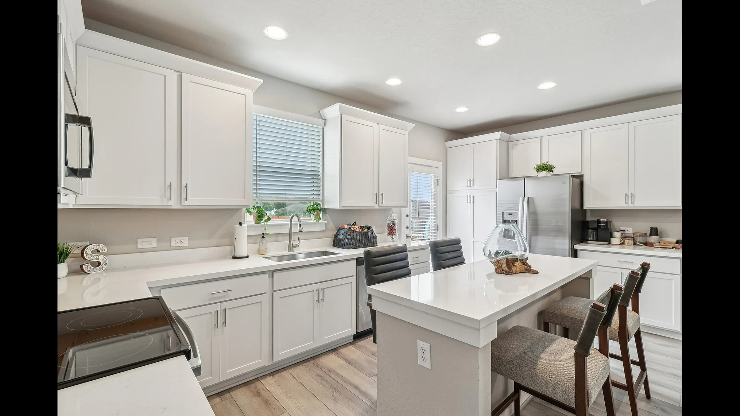 Bright and modern kitchen featuring sleek white cabinetry, elegant countertops, and a stylish island with comfortable seating.