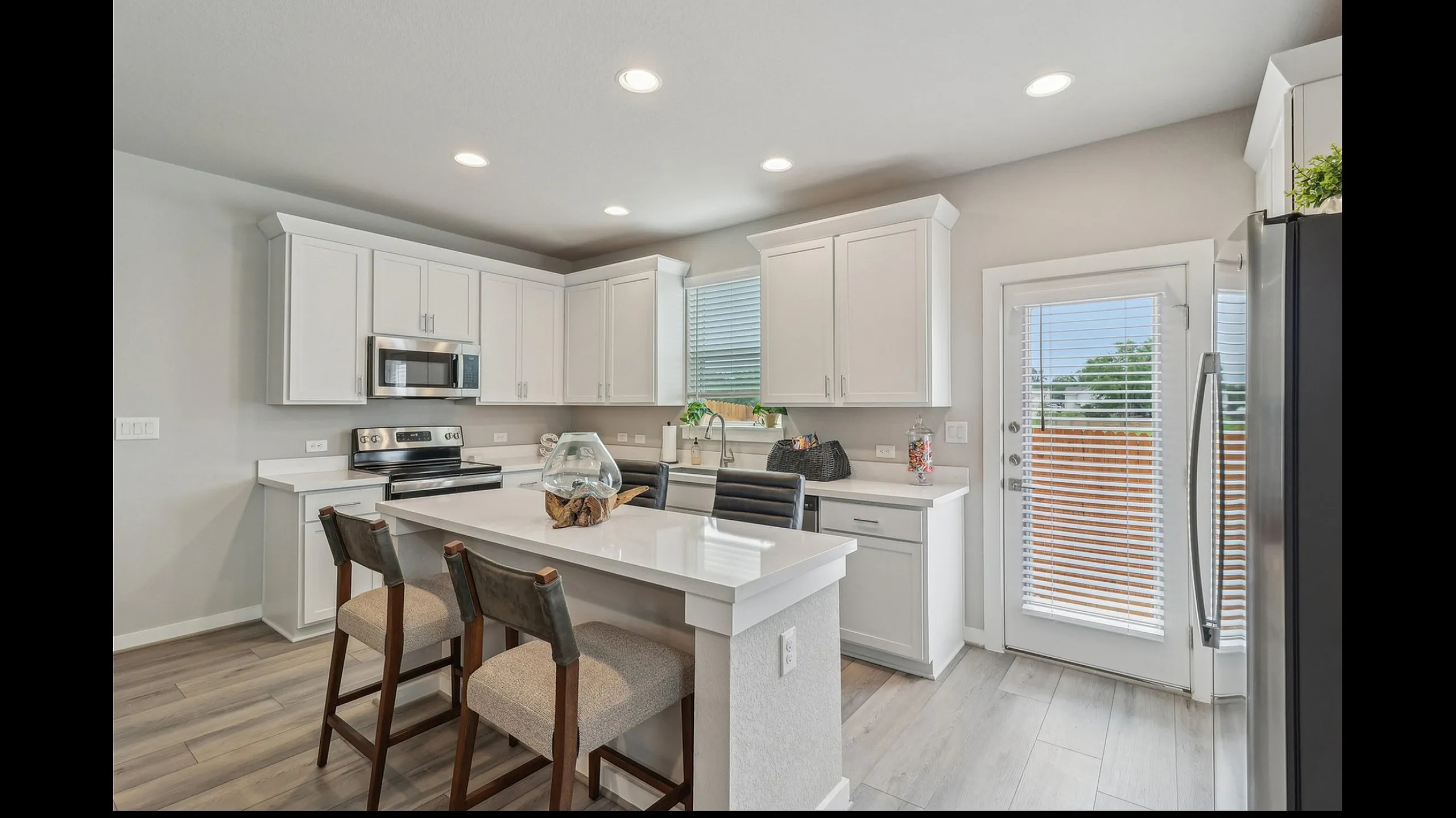 Bright and modern kitchen featuring sleek white cabinetry, stainless steel appliances, and a stylish island with seating.