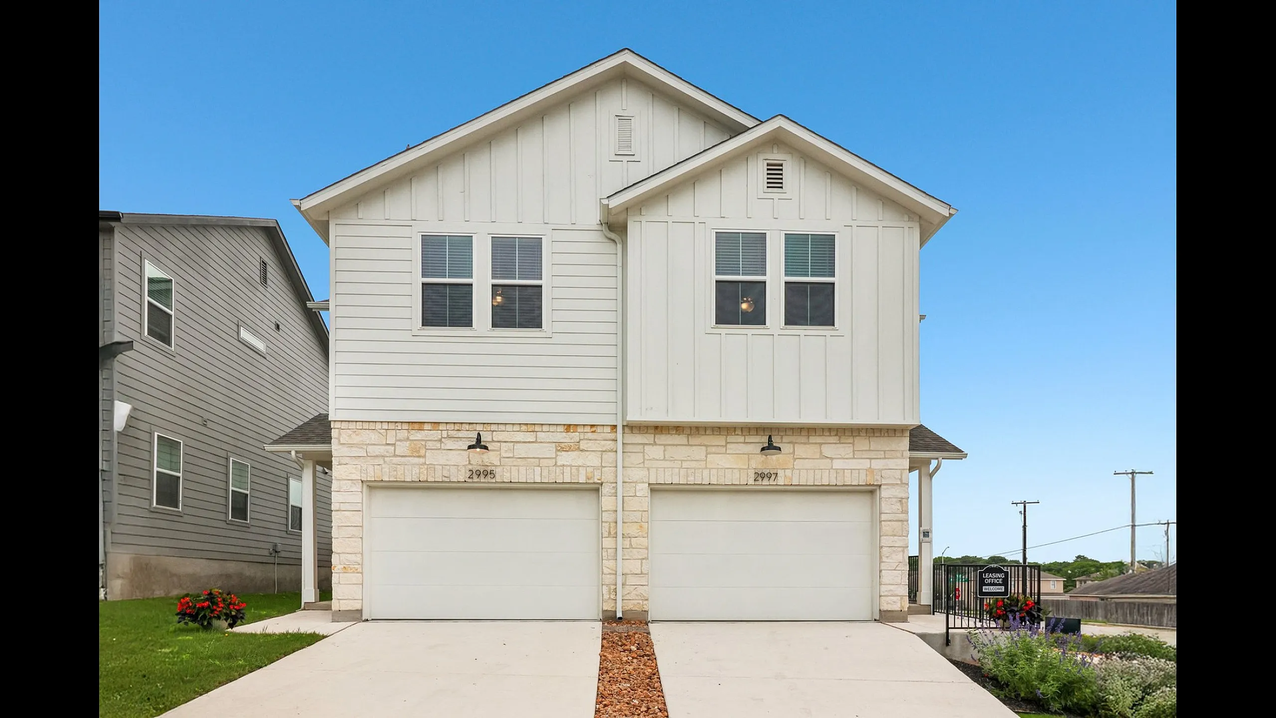 Charming modern duplex with sleek white exterior and landscaped front yard, offering spacious living in a suburban setting.