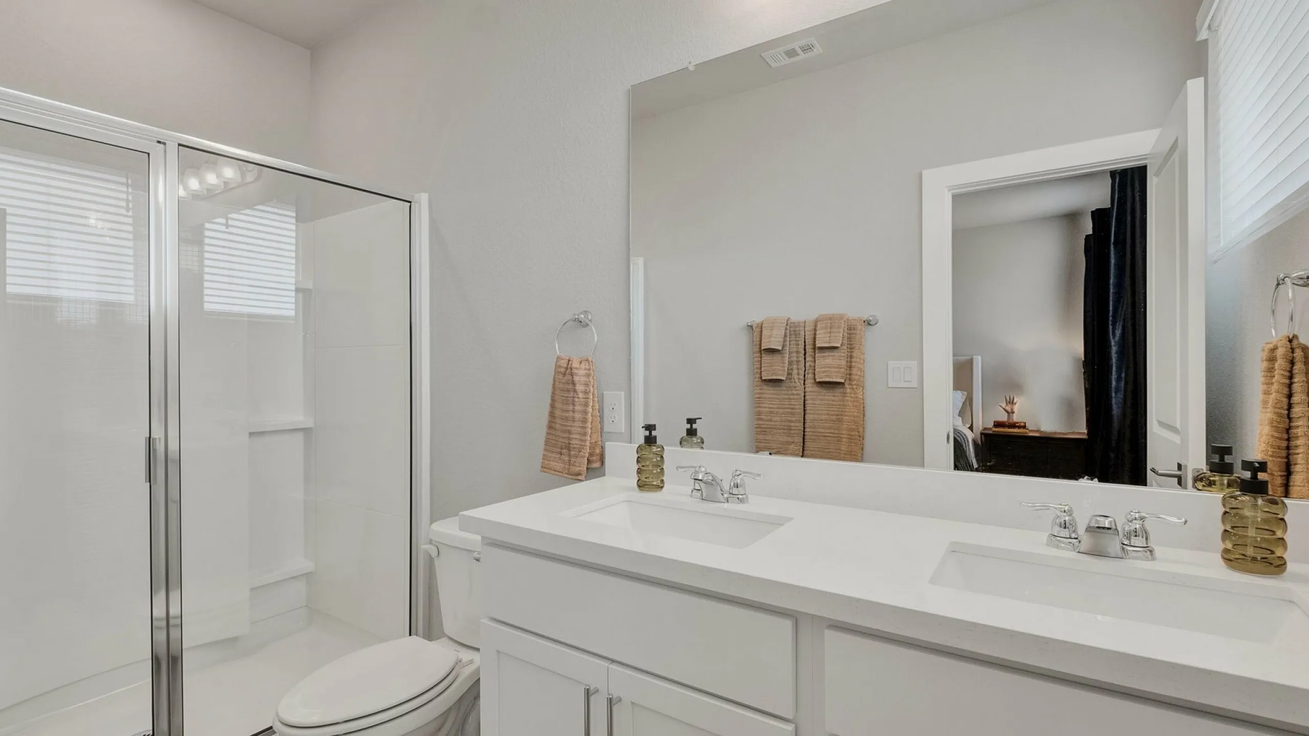 Modern bathroom featuring a spacious glass shower, elegant dual sinks, and stylish light fixtures.