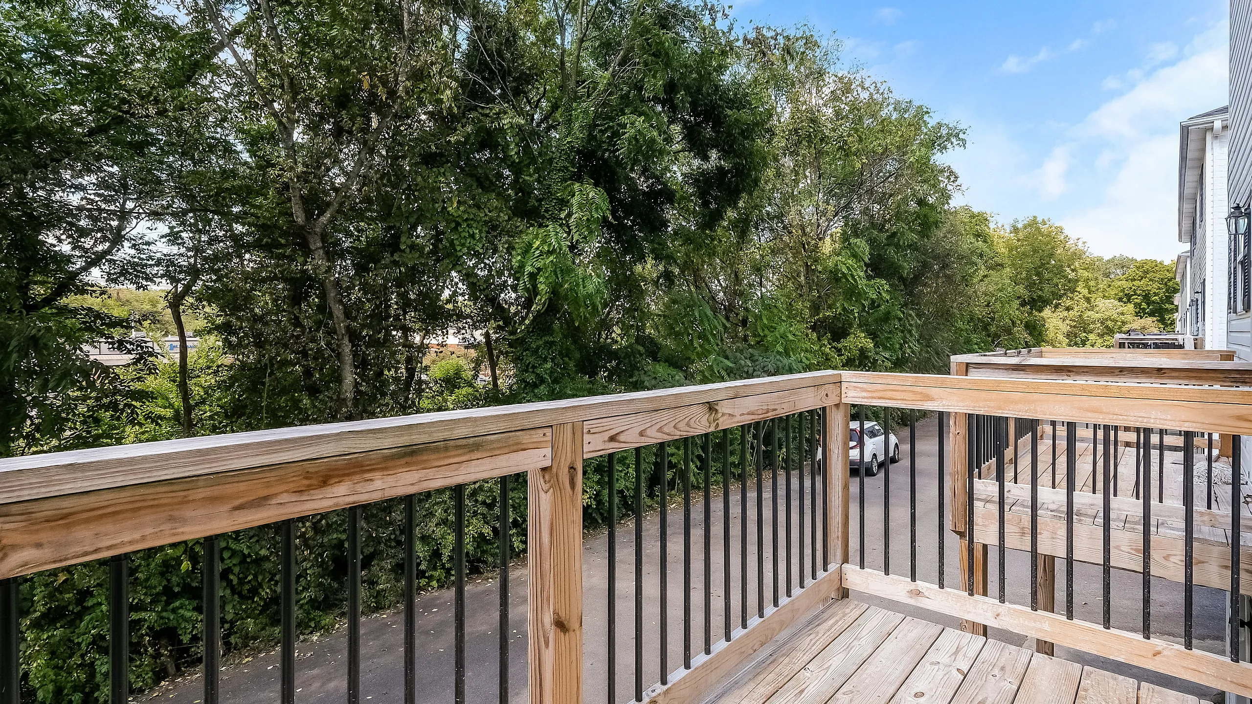 Charming wooden balcony offering a serene view of lush green trees, perfect for relaxing and enjoying nature.