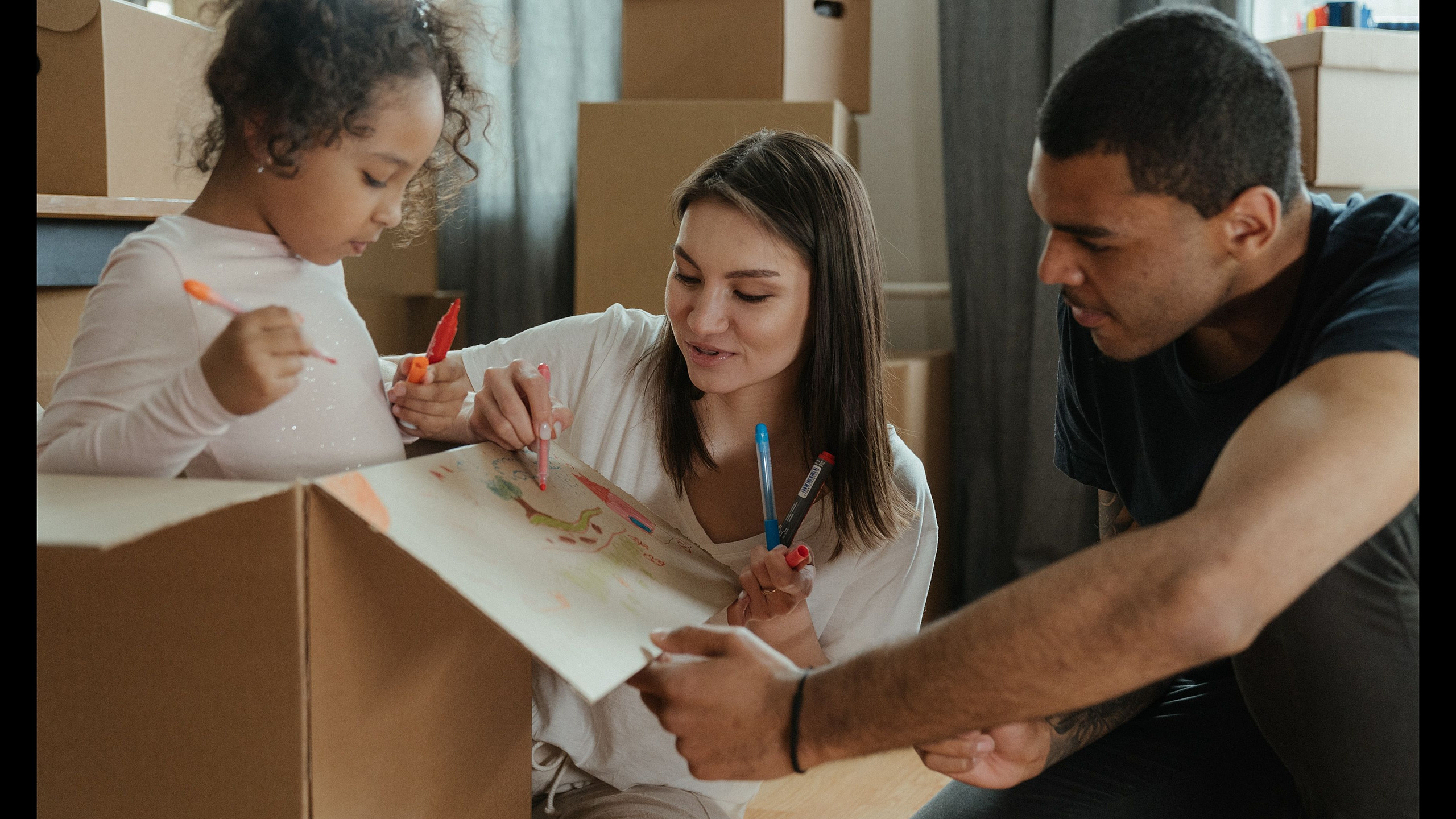 Happy family enjoying creative time together while packing in a cozy new home filled with spacious boxes.