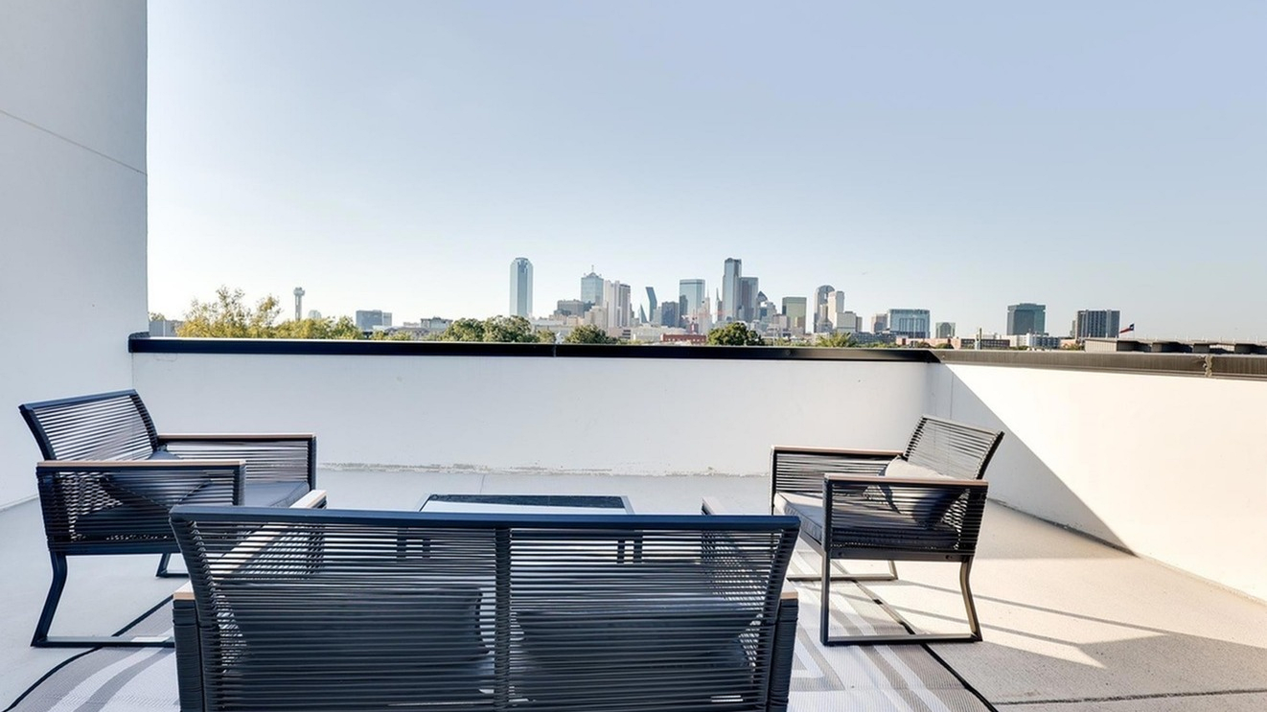 Chic rooftop patio with contemporary seating offering panoramic cityscape views, ideal for relaxing and entertaining.