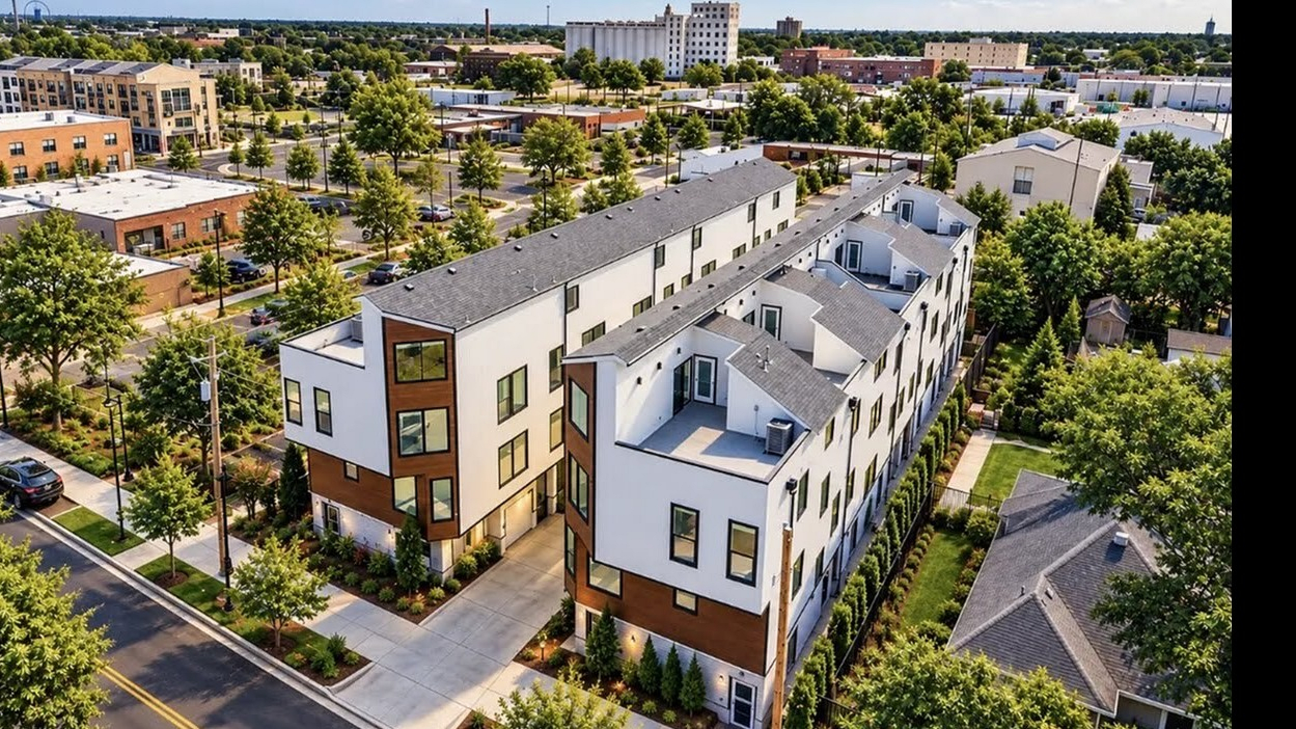 Modern townhouse complex with stylish architecture surrounded by lush greenery in vibrant urban setting.