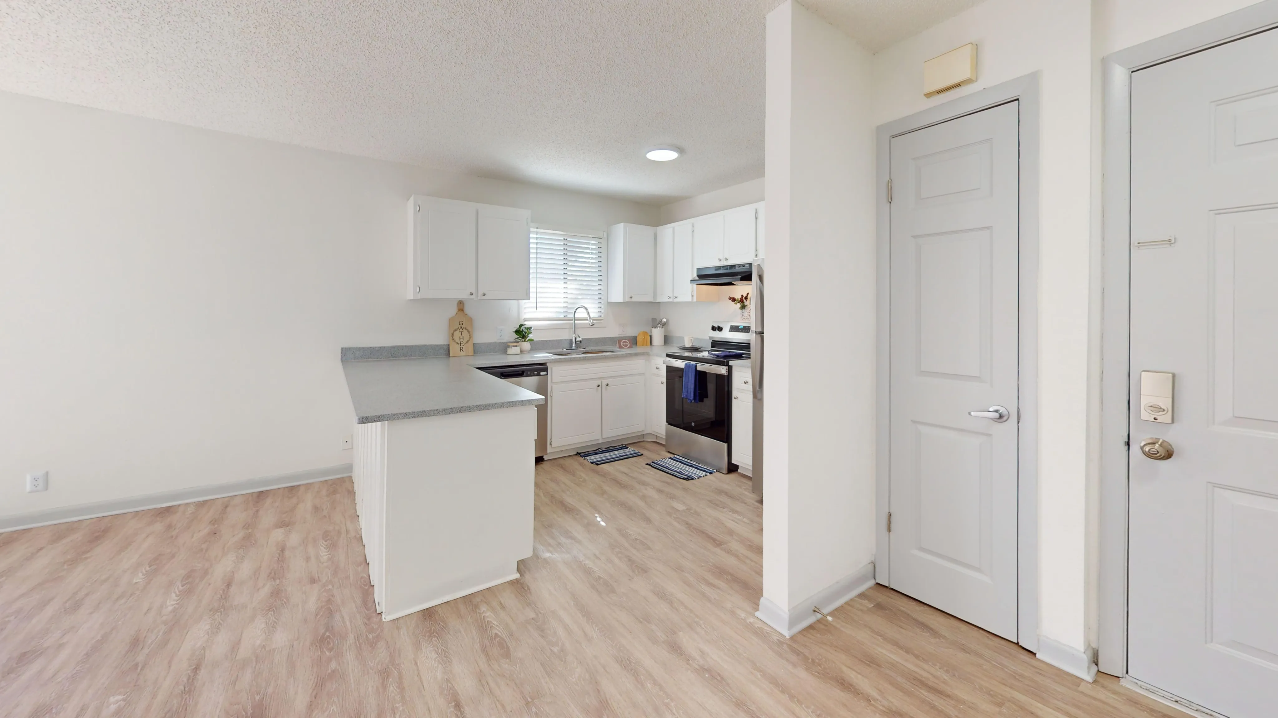 Bright, open kitchen with white cabinets and sleek countertops, featuring stainless steel appliances.