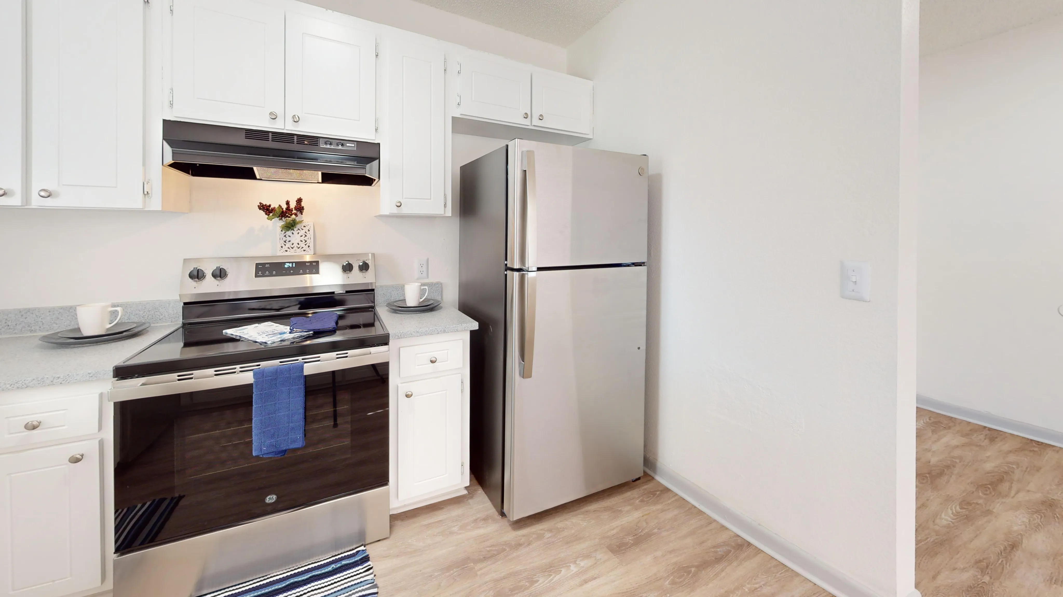 Bright and modern kitchen featuring stainless steel appliances, white cabinetry, and hardwood flooring.