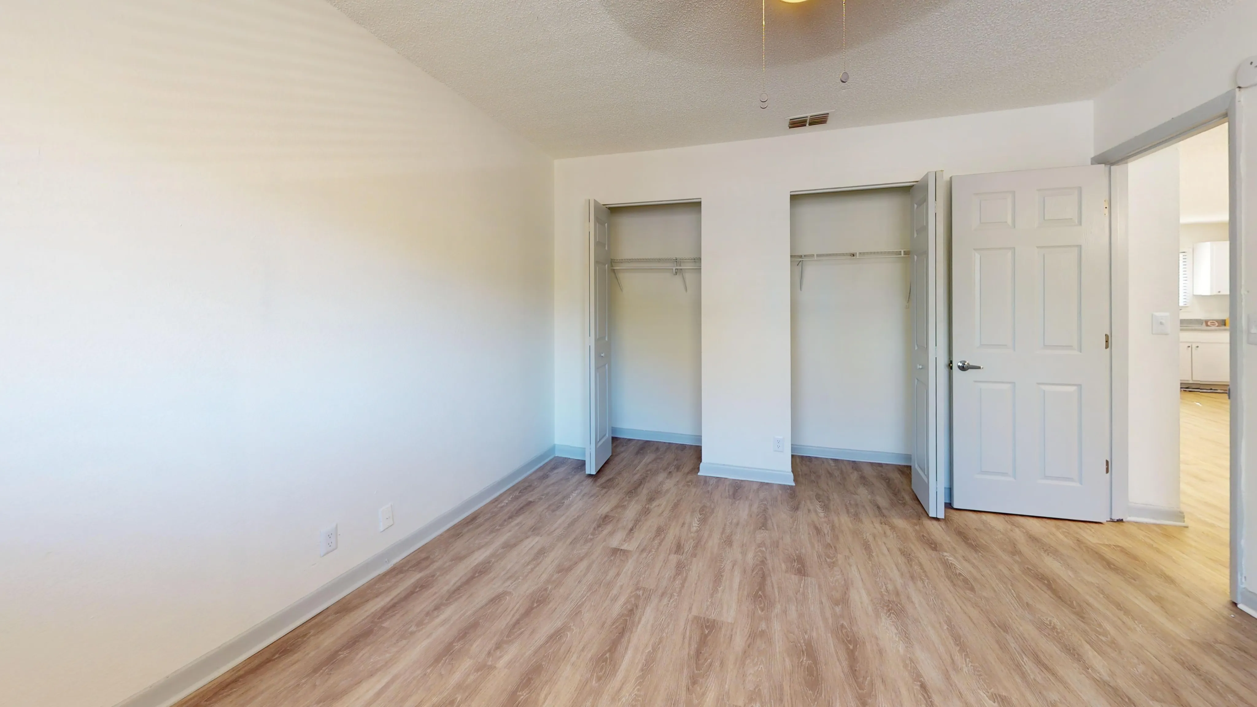 Bright bedroom with wooden floors and double open closets.