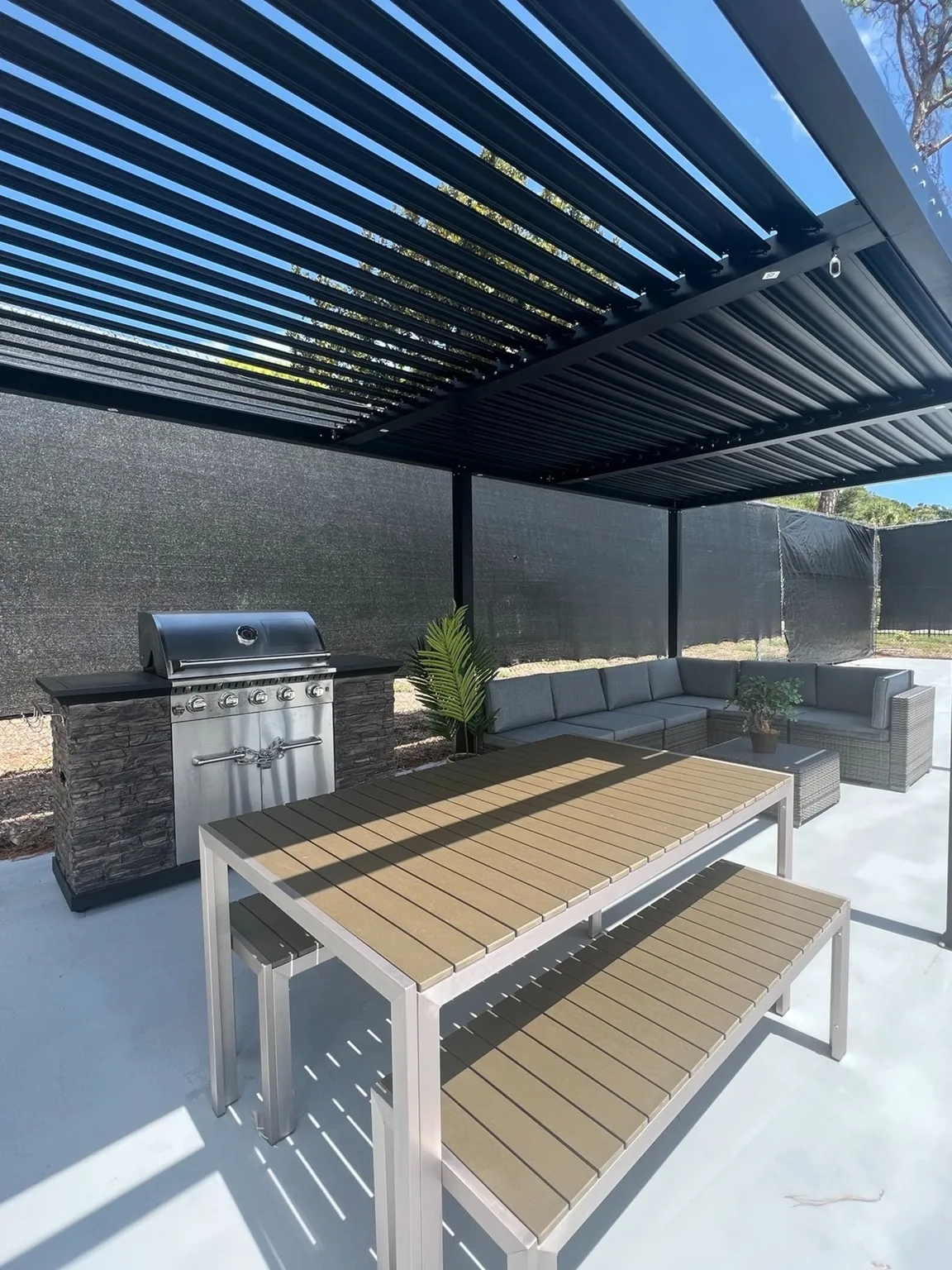 Outdoor kitchen with grill, lounge area and picnic tables