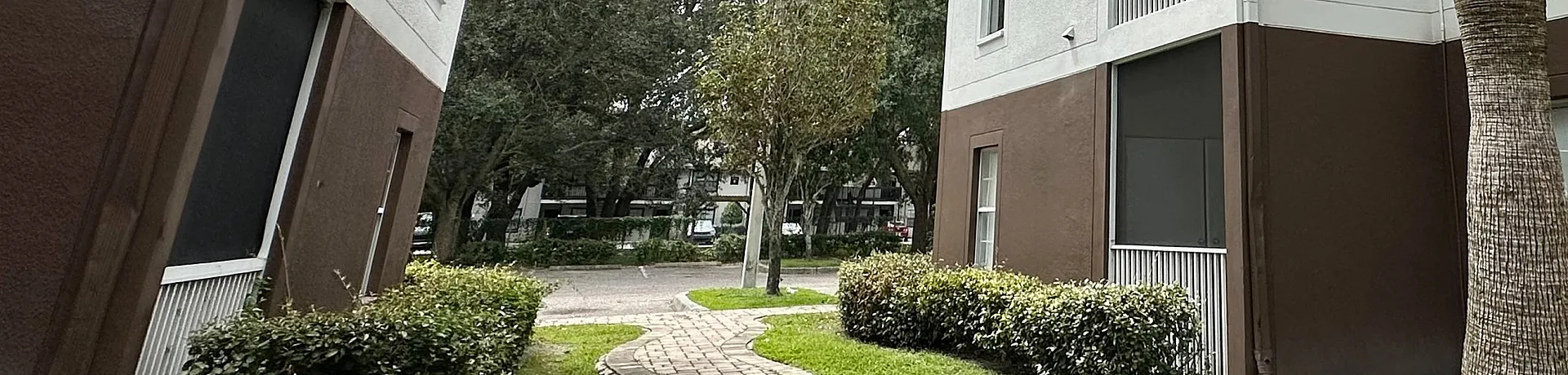 Charming apartment complex with modern architecture, lush greenery, and inviting walkways under a picturesque sky.