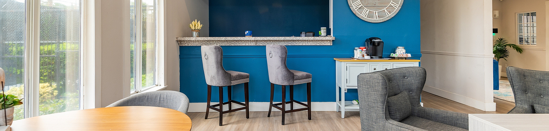 Chic apartment lounge featuring a modern caf&eacute;-style breakfast bar, plush seating, and natural light from large windows.