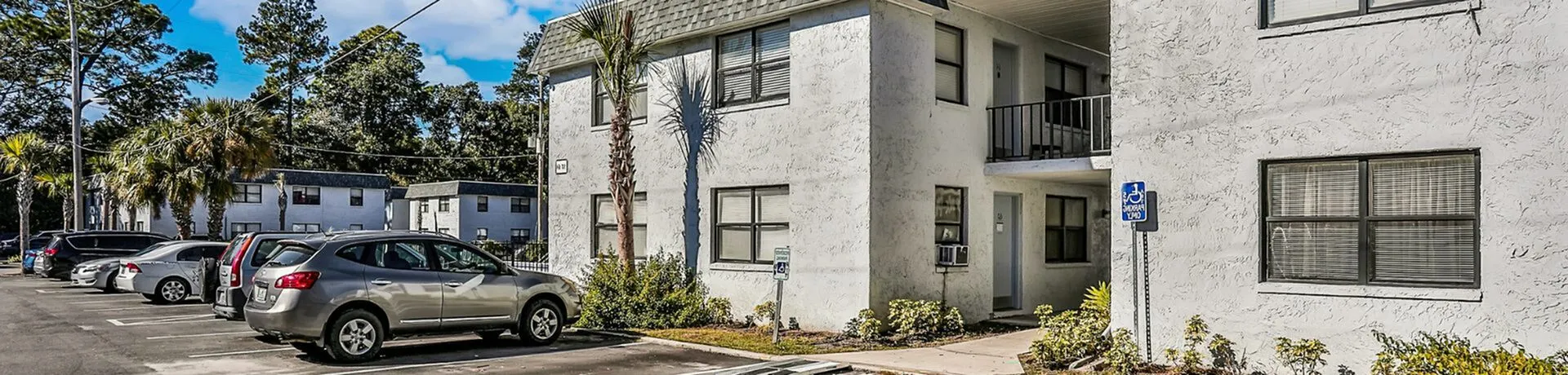 Charming residential building with modern facade, surrounded by lush greenery and ample parking space.