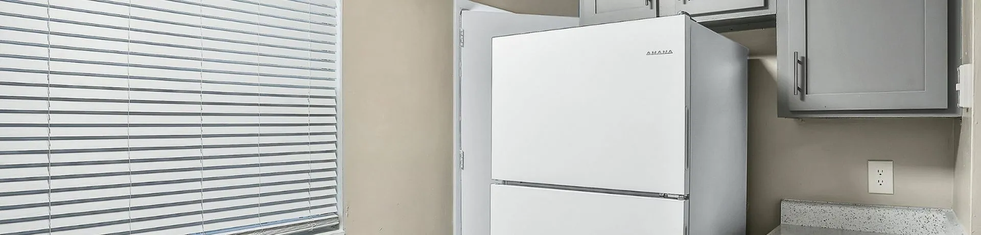 Bright kitchen corner featuring a modern white refrigerator and sleek gray cabinets.