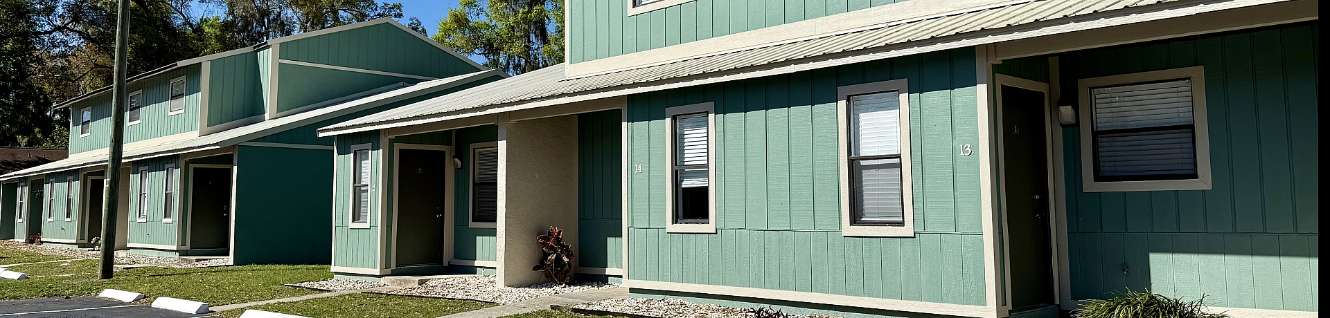 Charming green townhouses with modern architecture nestled in a serene neighborhood surrounded by lush greenery.