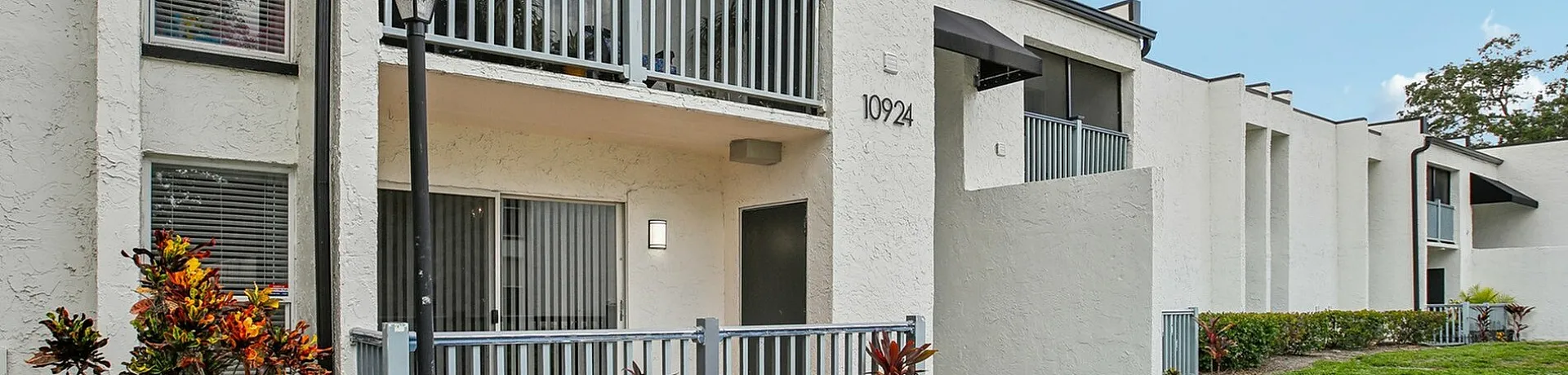 Charming modern apartment with a balcony, beautiful windows, and lush greenery in a serene neighborhood setting.