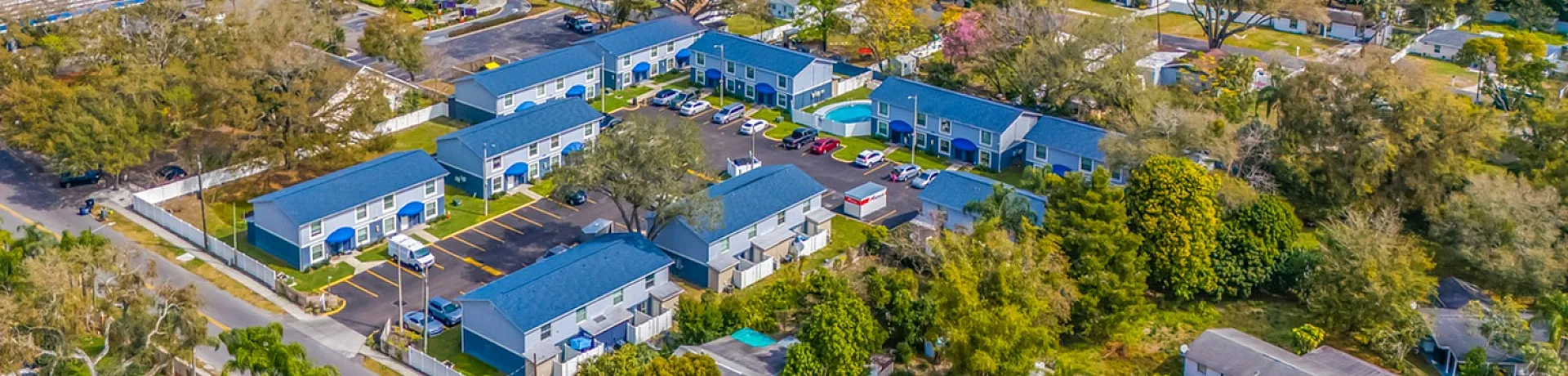 Vibrant aerial view of a lively neighborhood with colorful buildings, lush greenery, and a nearby amusement park.