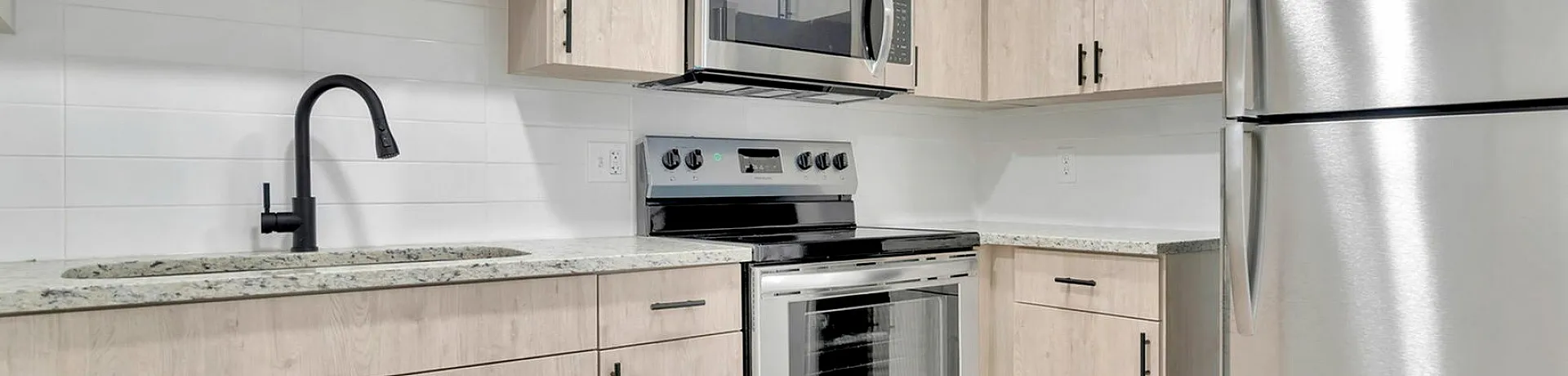 Modern kitchen design featuring sleek stainless steel appliances, elegant light wood cabinetry, and a stylish chrome faucet.