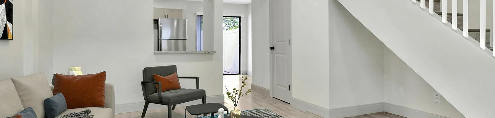 Modern living room with elegant staircase, stylish decor, and open layout leading to a contemporary kitchen.