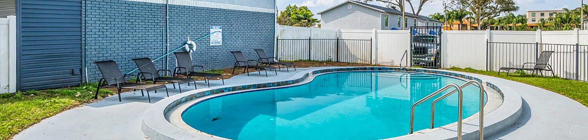 Inviting outdoor pool area with lounge chairs and lush green surroundings, perfect for relaxation and leisure.