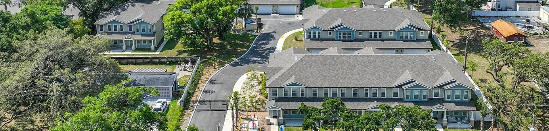 Inviting aerial view of a charming residential area with modern apartments surrounded by lush greenery, offering easy city access and vibrant community life.