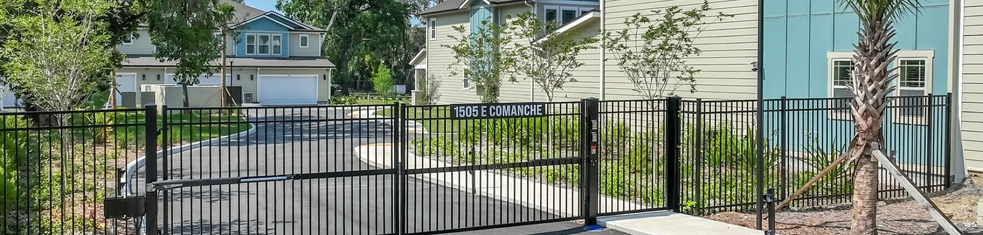 Charming gated community entrance with modern homes, lush landscaping, and a serene environment.