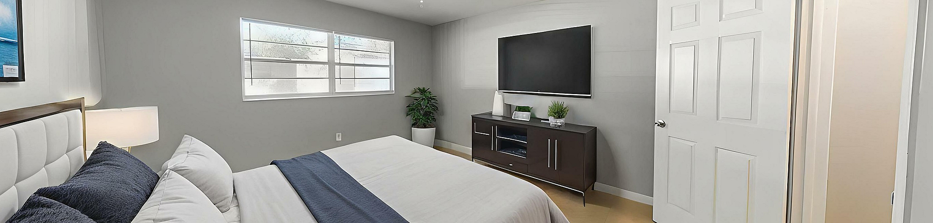 Bright and elegant bedroom featuring a plush bed with stylish pillows, modern TV setup, and large window for natural light.