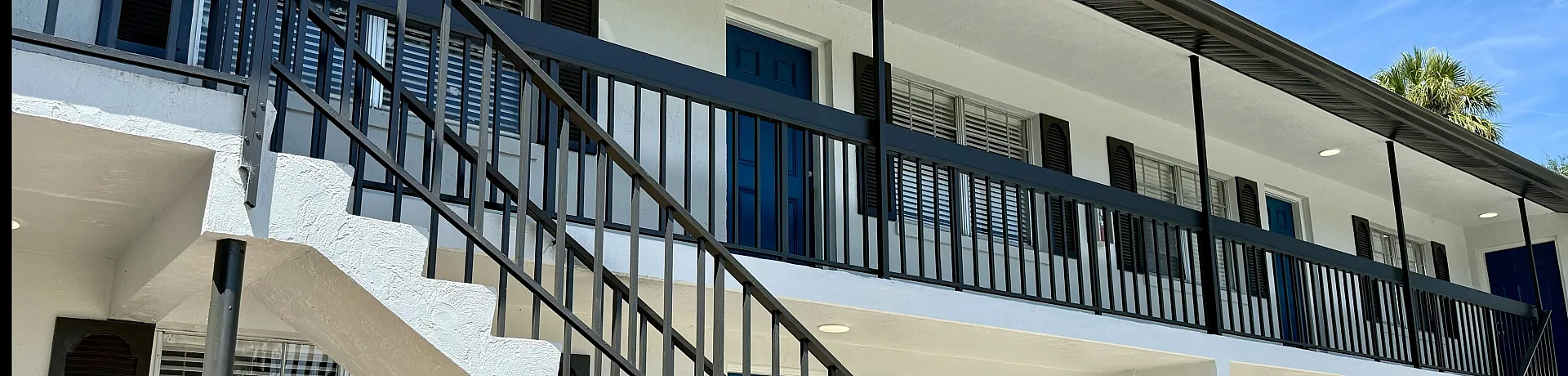 Charming two-story apartment building with modern railings and fresh paint, offering vibrant and comfortable living spaces.