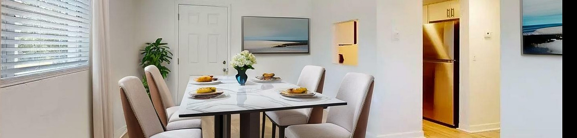 Elegant dining room with stylish table set for four, natural light streaming through large window, and contemporary decor.