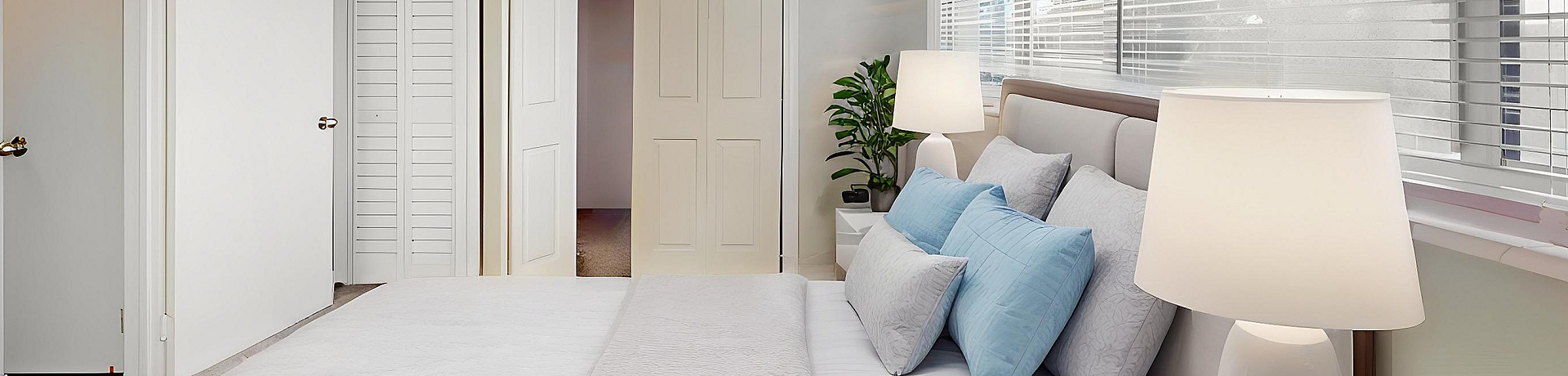 Bright modern bedroom with large windows, sleek ceiling fan, and cozy decor featuring elegant bedding and chic lighting.