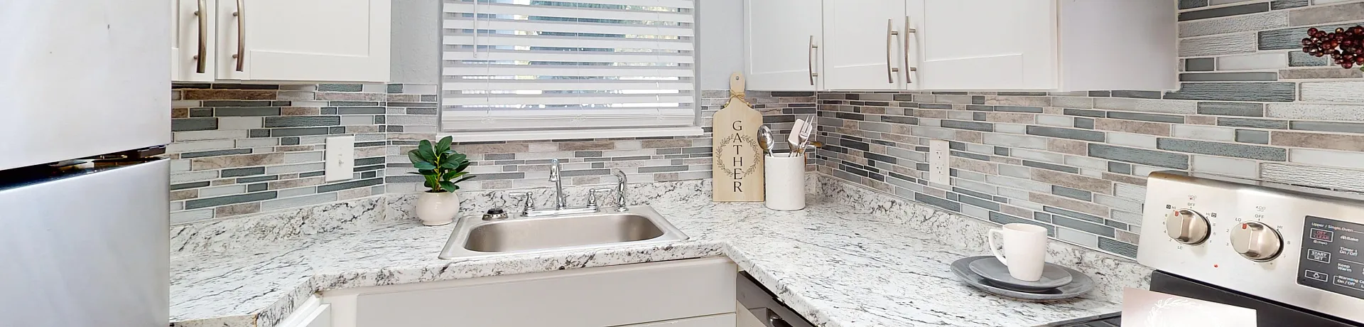 Bright and modern kitchen with sleek stainless steel appliances, elegant granite countertops, and stylish mosaic backsplash.