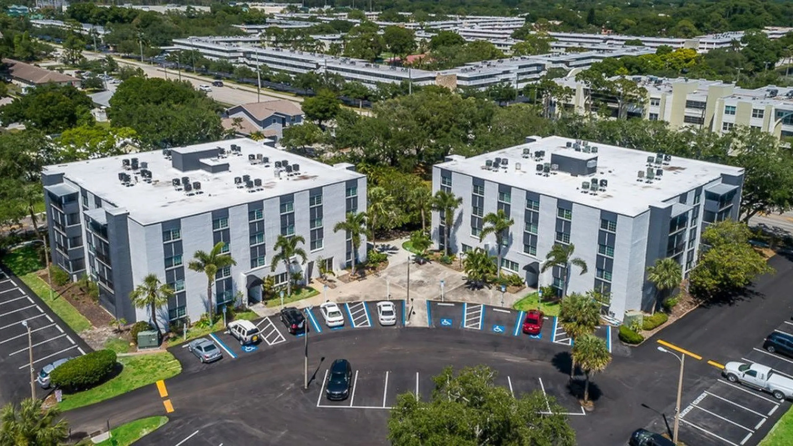 Charming apartment complex with modern architecture surrounded by lush greenery and spacious parking, offering a serene living environment.