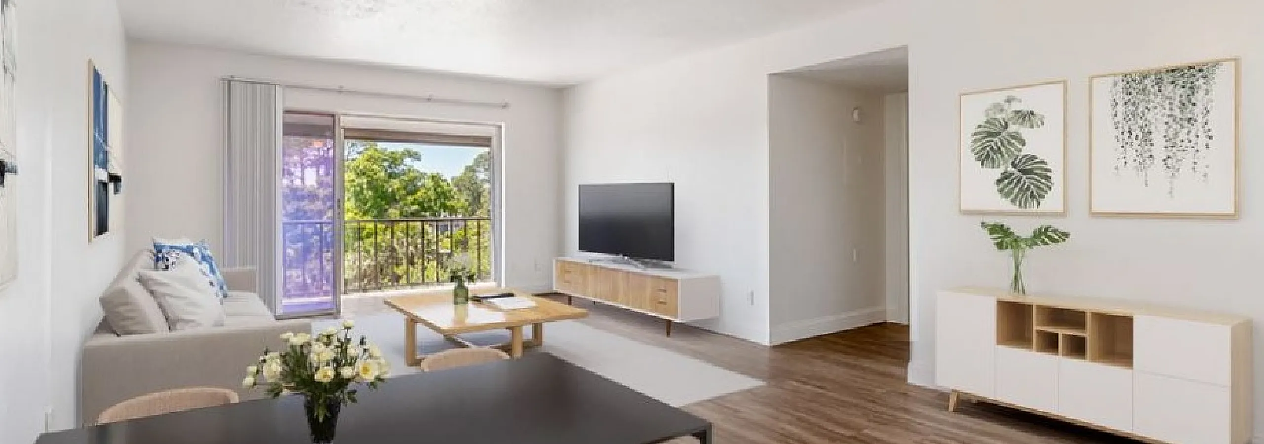 Bright and airy living space featuring a chic open-plan design with modern furniture, wooden flooring, and a scenic balcony view.