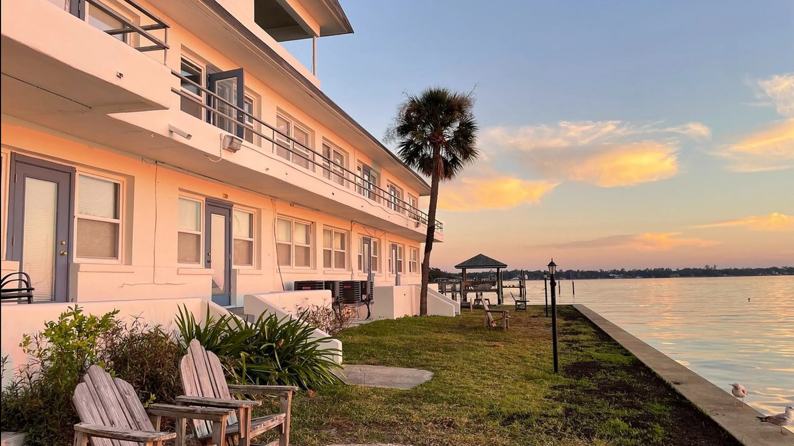 Charming waterfront apartment with sunset views, outdoor seating, and lush greenery, offering serene lakeside living.