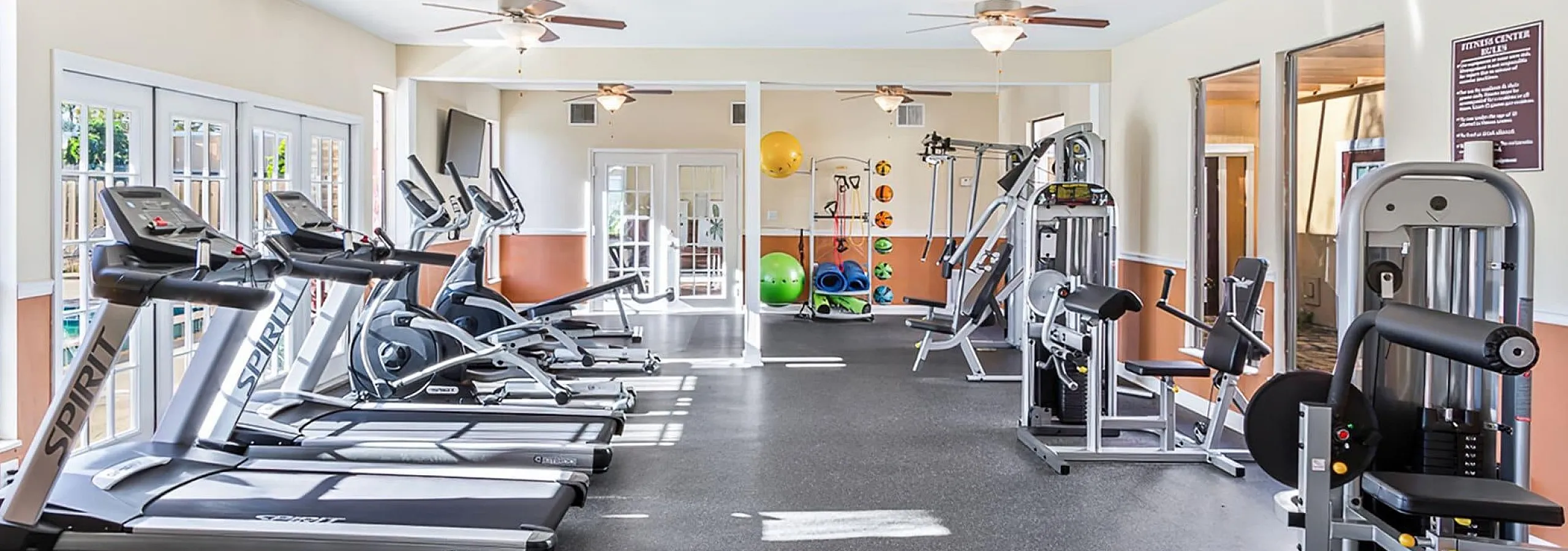 Bright and spacious gym with state-of-the-art exercise equipment, including treadmills and strength machines, offering a welcoming fitness environment.