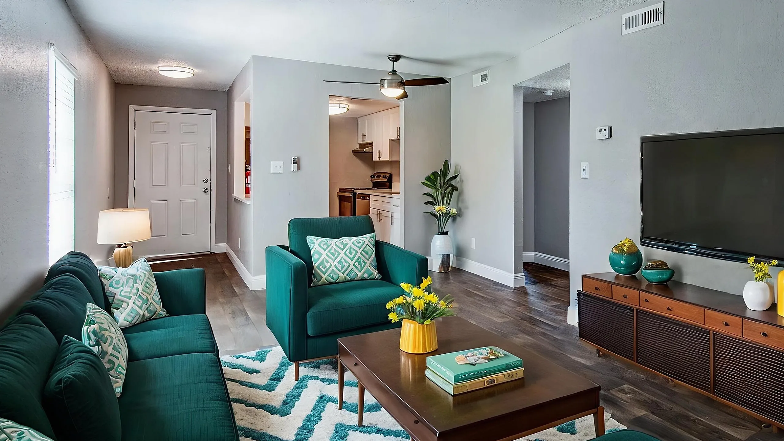 Inviting living room with plush teal furniture, contemporary decor, and an open entryway to a modern kitchen.