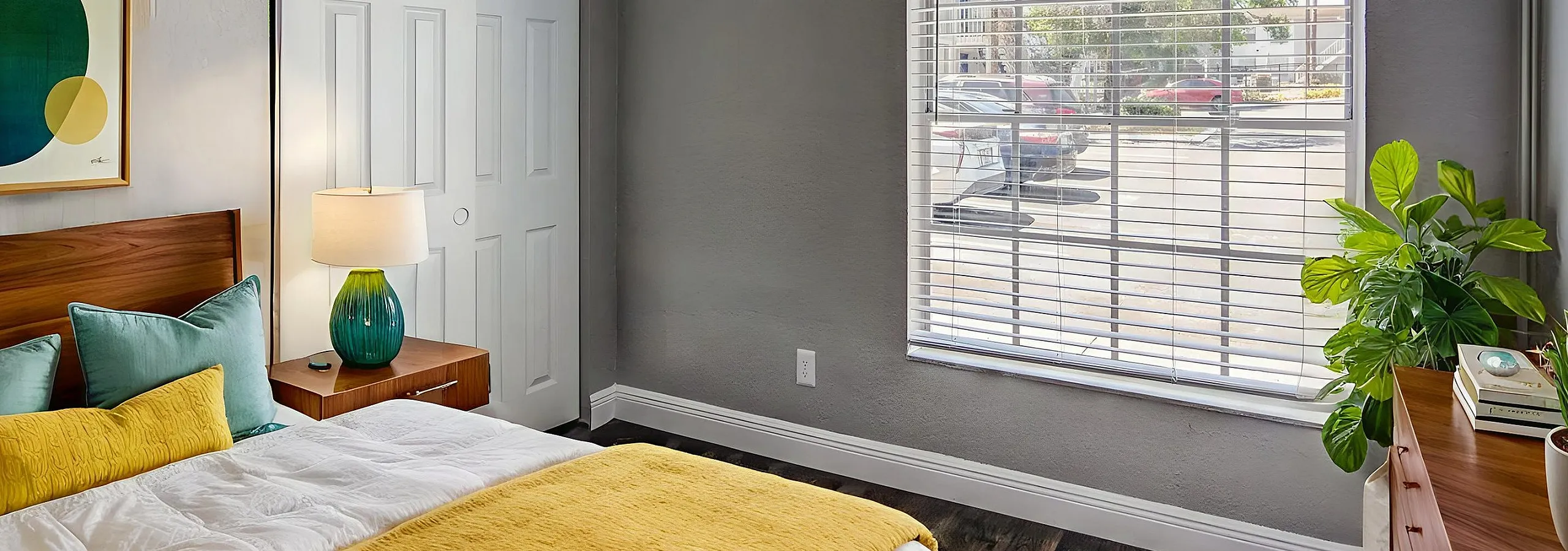 Inviting bedroom featuring a cozy bed with vibrant yellow accents, modern decor, and a large window with a view, perfect for a relaxing retreat.