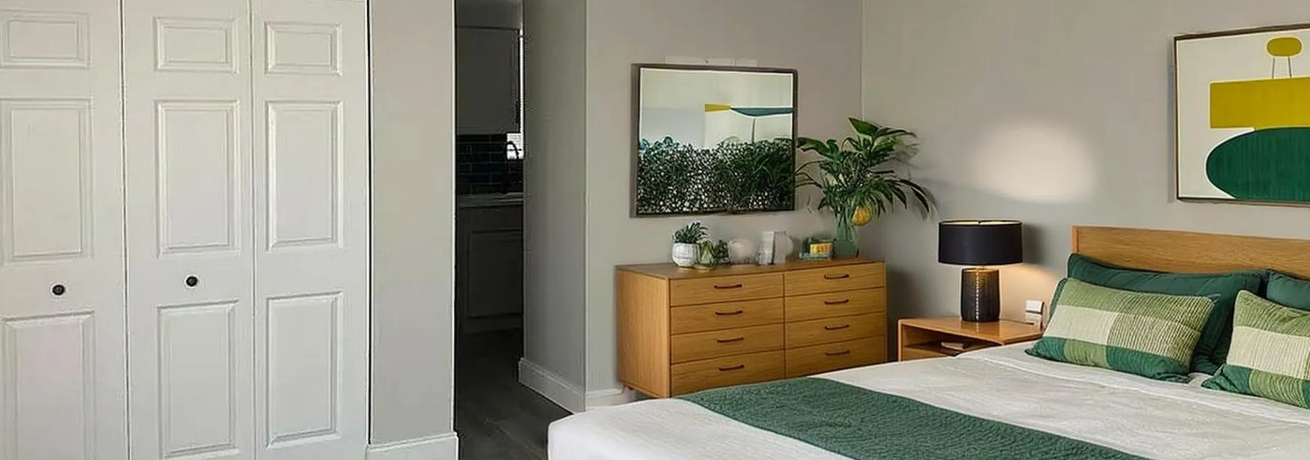 Inviting bedroom with modern decor, elegant wood furniture, and a cozy atmosphere showcasing contemporary art and a plush rug.