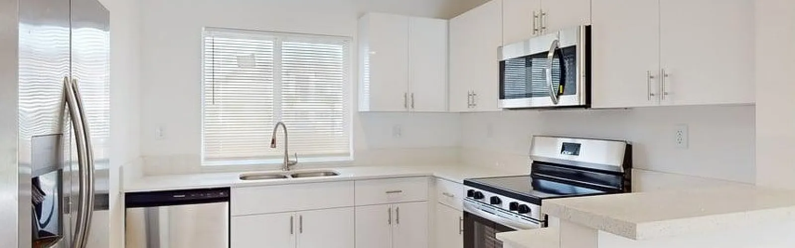 Bright, modern kitchen with sleek stainless steel appliances, elegant white cabinetry, and beautiful wood flooring.