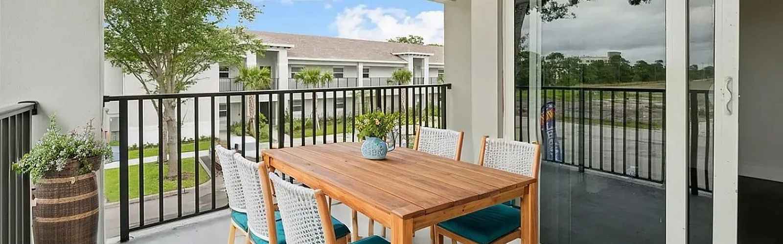 Inviting balcony with stylish outdoor dining set, offering tranquil views of lush greenery and modern architecture.